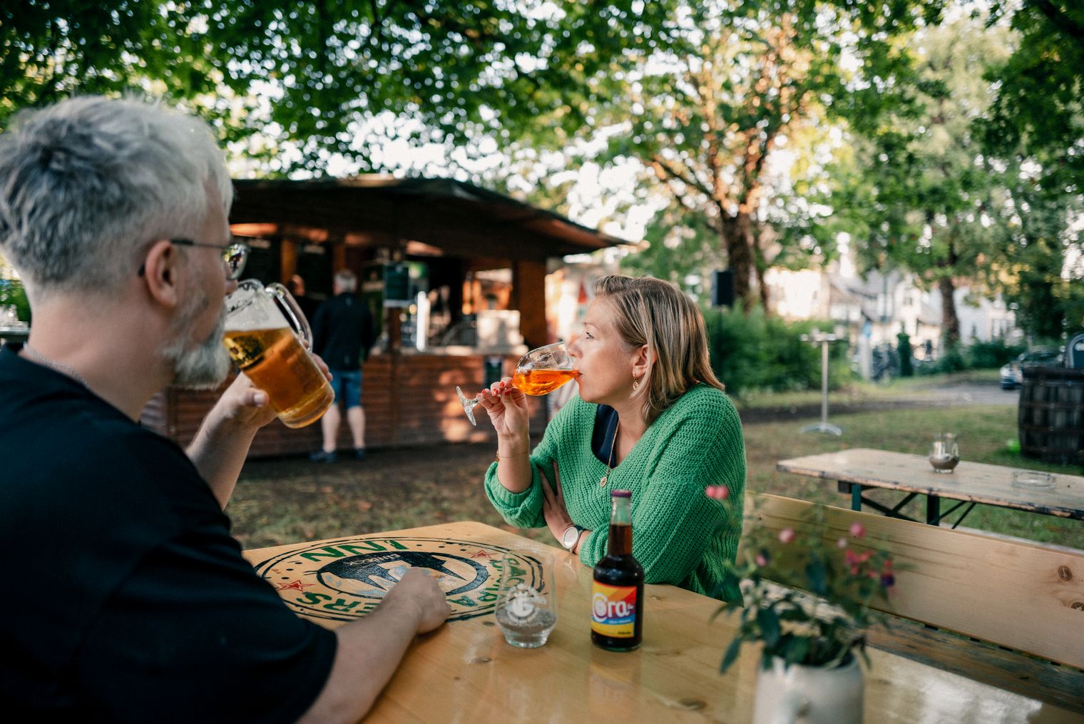 Zwei Personen sitzen zusammen im Einbecker Biergarten und trinken Kaltgetränke.