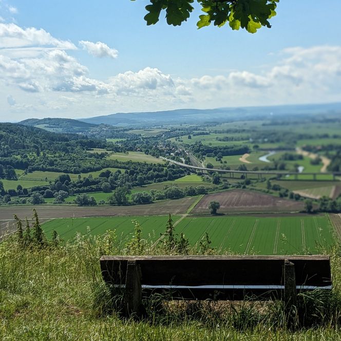 Ein Holzbank dient als Sitzplatz für einen tollen Ausblick in die Landschaft.