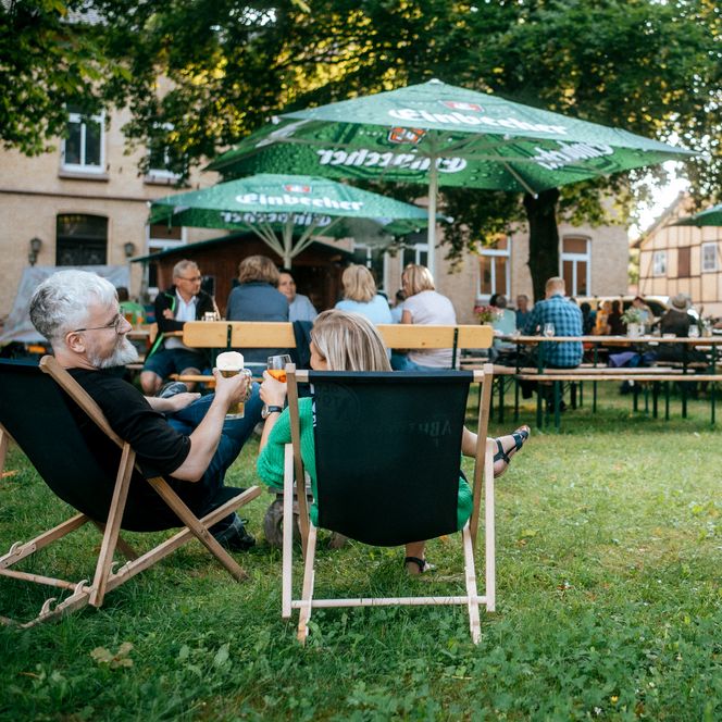 Menschen auf Stühlen und Bänken mit Getränken.