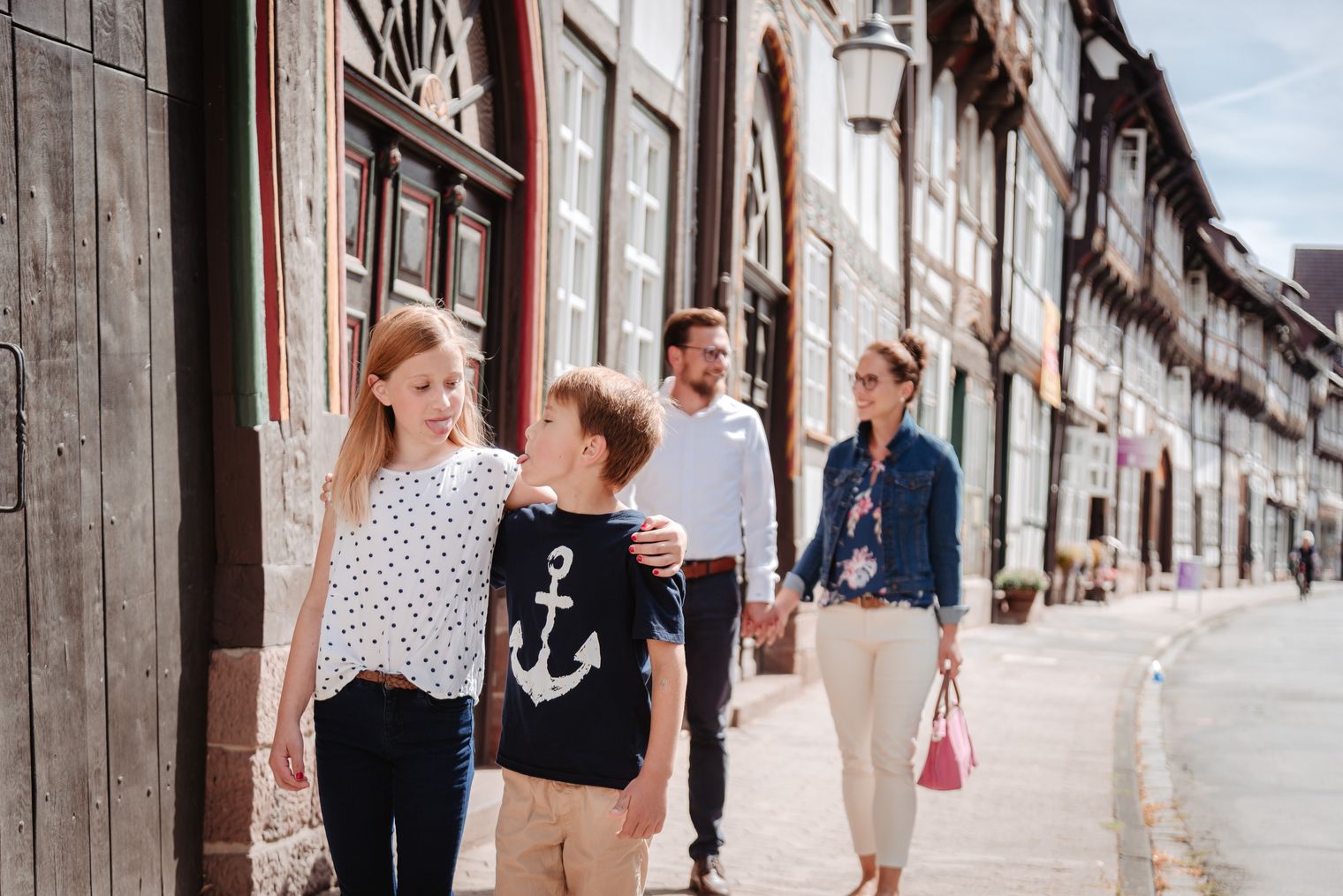 Familie mit zwei Kindern spaziert durch historische Fachwerkstraße in Altstadt