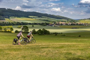 Zwei Personen auf dem Fahrrad fahren durch die weite Einbecker Landschaft.