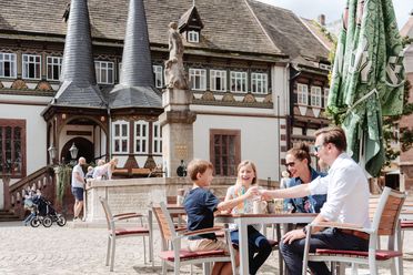 Eine Familie sitzt im Außenbereich des Restaurants Brodhaus auf dem Marktplatz. Sie essen und trinken.