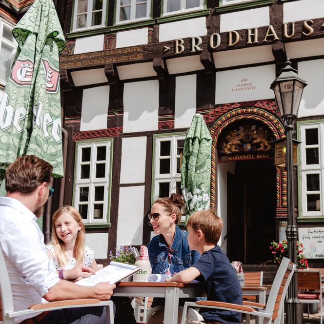 Eine Familie mit zwei Kindern sitzt an einem Tisch vor dem Brodhaus.