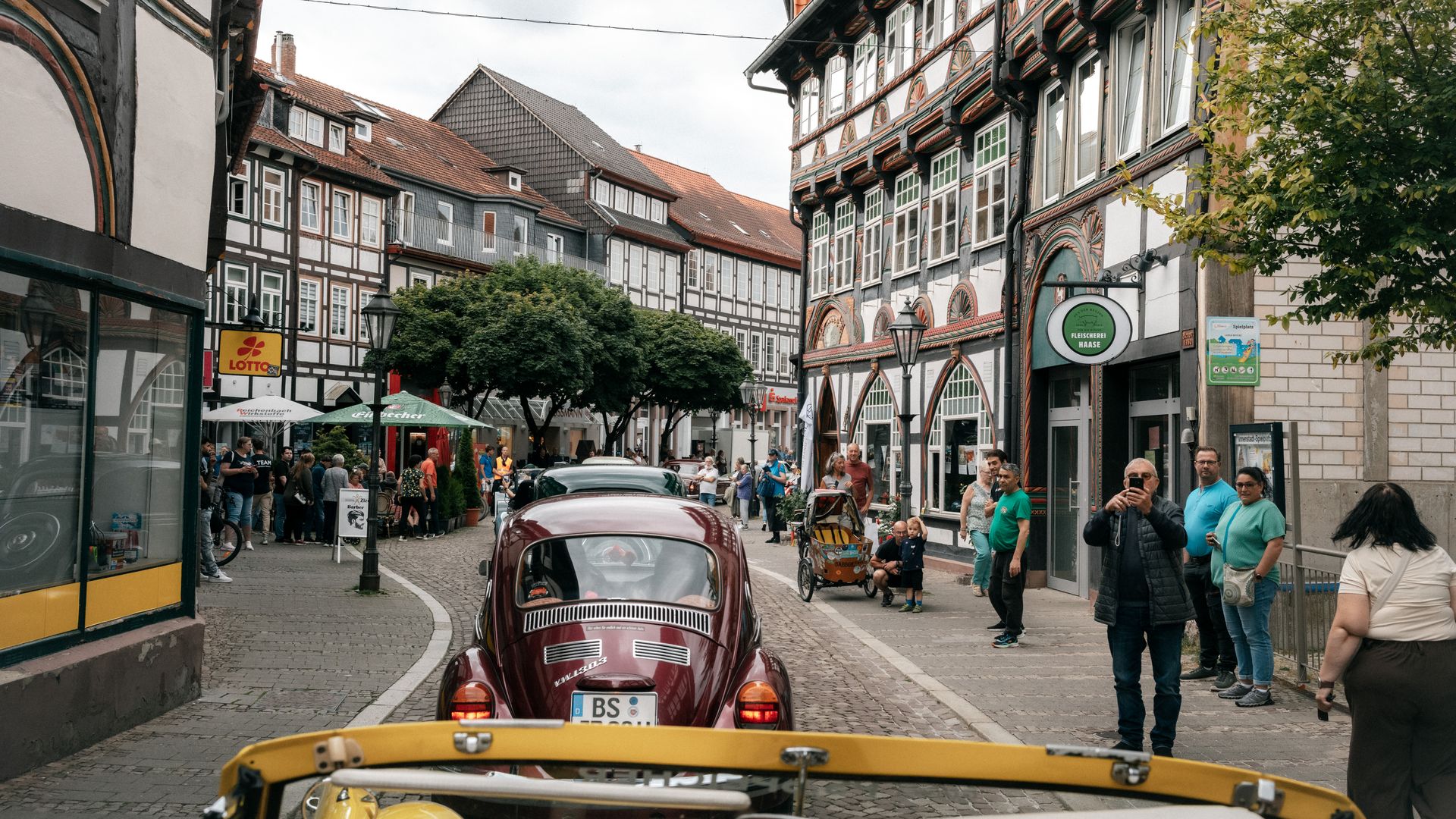 Roter VW Käfer bei einer Oldtimer-Rallye vor historischen Fachwerkhäusern in Einbeck.