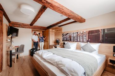 2 Menschen in einem Hotelzimmer im Fachwerkstil.