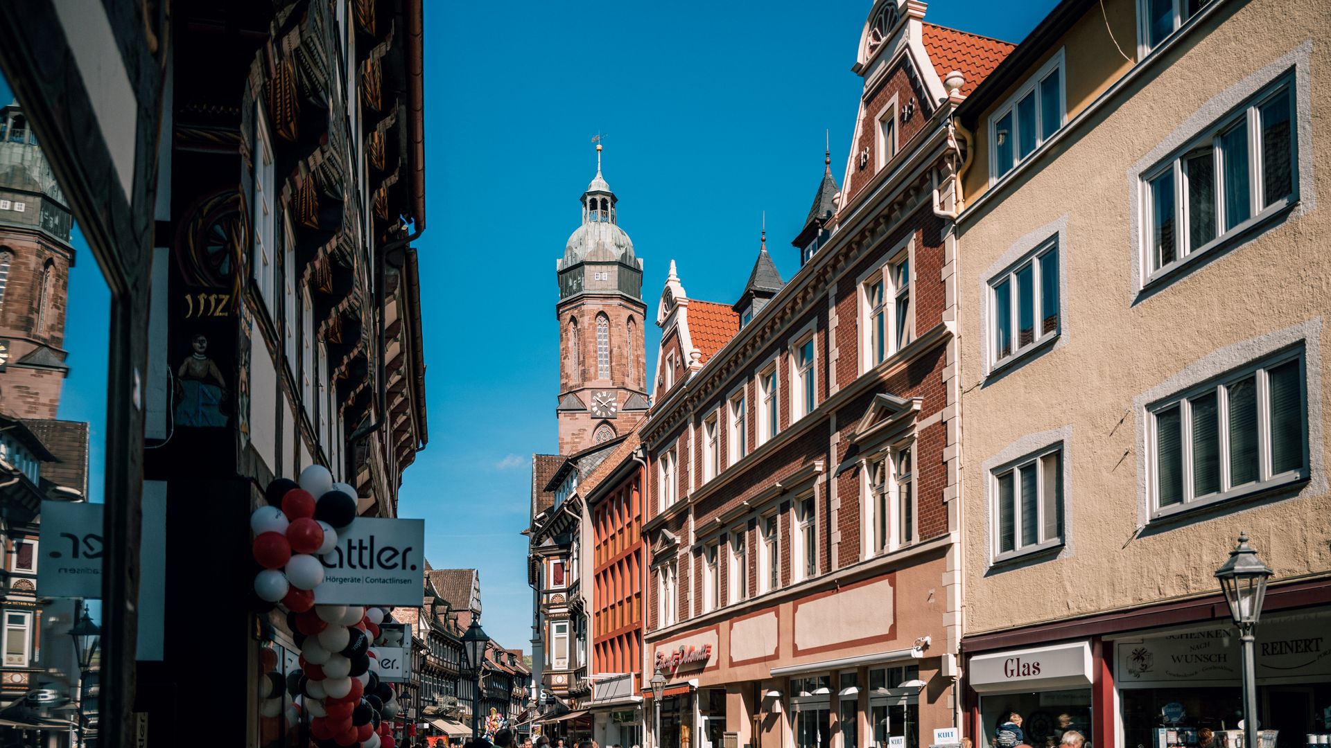 Die belebte Marktstraße beim Einbecker Eulenfest im Jahr 2022 bei blauem Himmel und Sonnenschein. In der Bildmitte der Marktkirchenturm.
