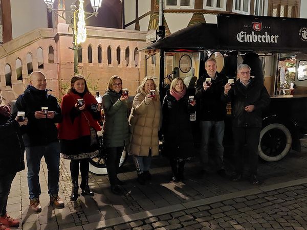 Bild mit mehreren Personen vor dem Alten Rathaus in Einbeck stehend. Die Personen halten ein Bockbier im Glas hoch und lächeln.