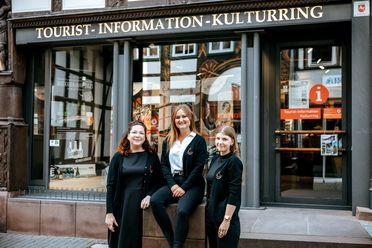 Drei Mitarbeiterinnen stehen vor der Tourist-Information Einbeck und lächeln in die Kamera.
