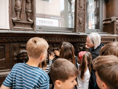 Kinder entdecken das Fachwerk. Kinder ertasten mit einer Stadtführerin eine historische Fassade.