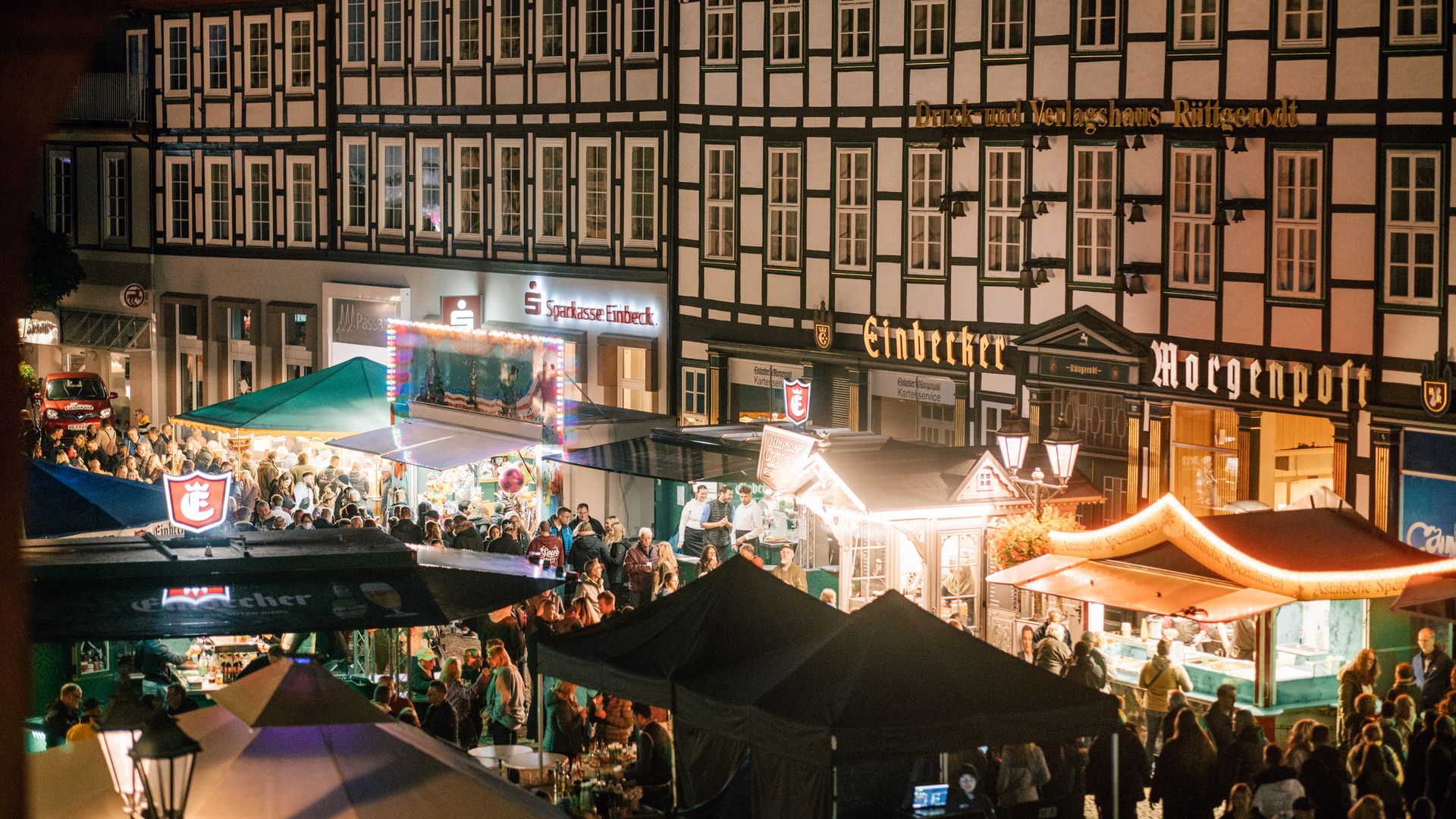 Der belebte Marktplatz beim Eulenfest mit vielen Menschen und beleuchteten Ständen.