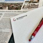 Bildschirm, Stift, Papier und Zeitung auf einem Tisch als Symbole für Öffentlichkeitsarbeit.