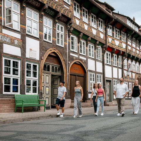 Mehrere Menschen laufen durch eine von Fachwerkhäusern gesäumte Straße.