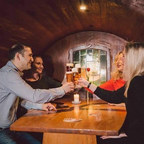 Freunde sitzen in einem alten und riesigen Bierfaß. Sie trinken Einbecker Bier und genießen.