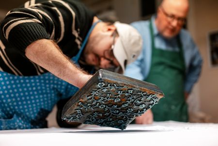 Teilnehmender druckt beim Blaudruck-Workshop in Einbeck ein Muster mit traditionellem Holzmodel.