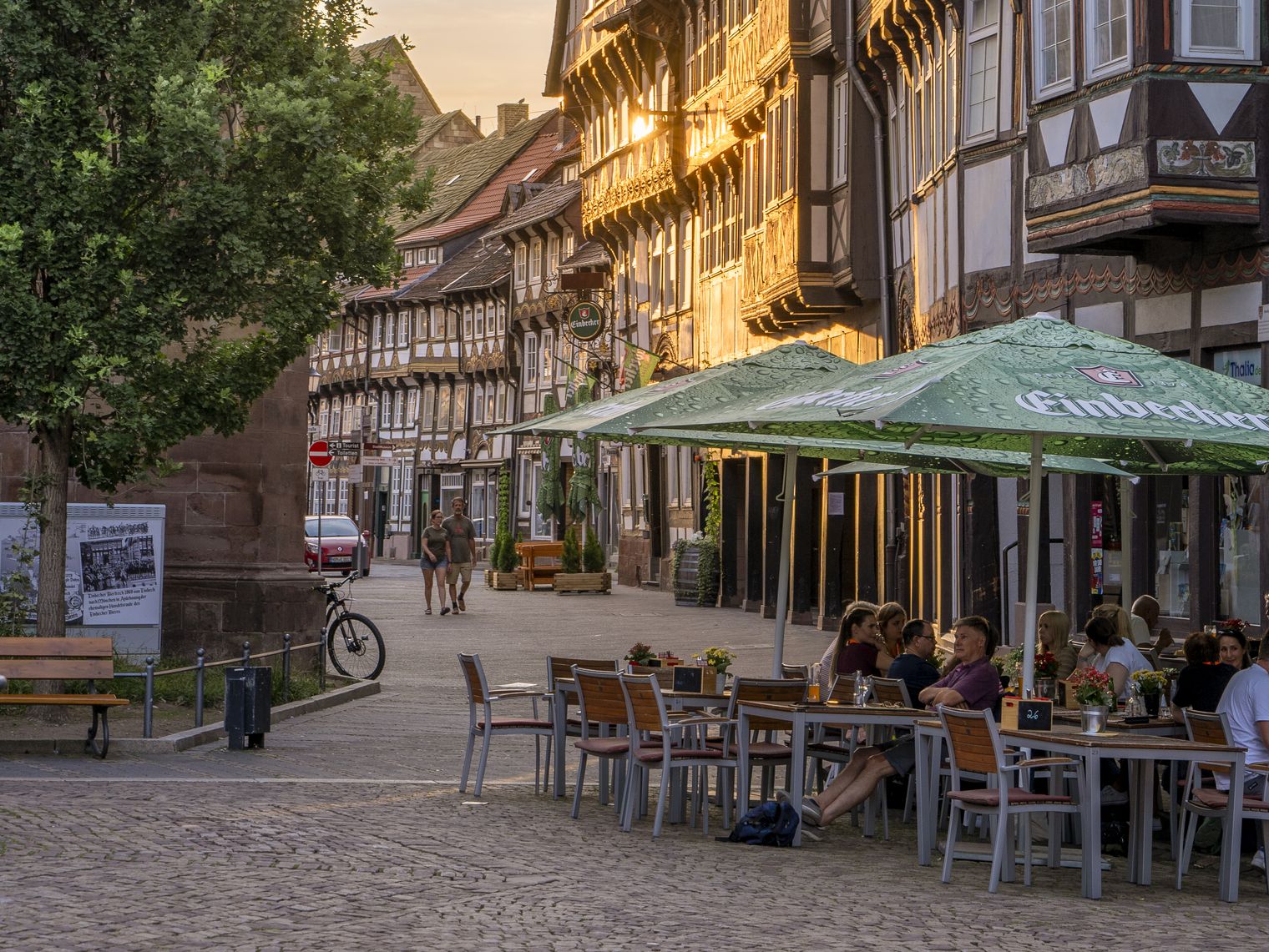 Fachwerkhäuser und Menschen, die im Außenbereich eines Restaurants sitzen auf dem Marktplatz bei Abendsonne.