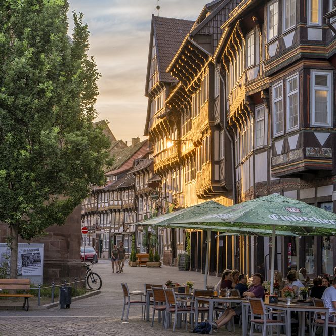 Fachwerkhäuser und Menschen, die im Außenbereich eines Restaurants sitzen auf dem Marktplatz bei Abendsonne.