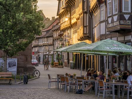 Fachwerkhäuser und Menschen, die im Außenbereich eines Restaurants sitzen auf dem Marktplatz bei Abendsonne.