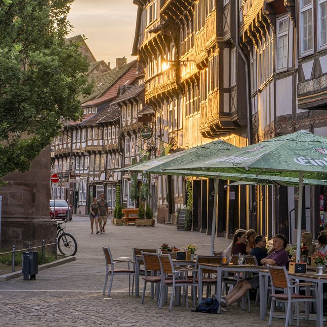 Fachwerkhäuser und Menschen, die im Außenbereich eines Restaurants sitzen auf dem Marktplatz bei Abendsonne.