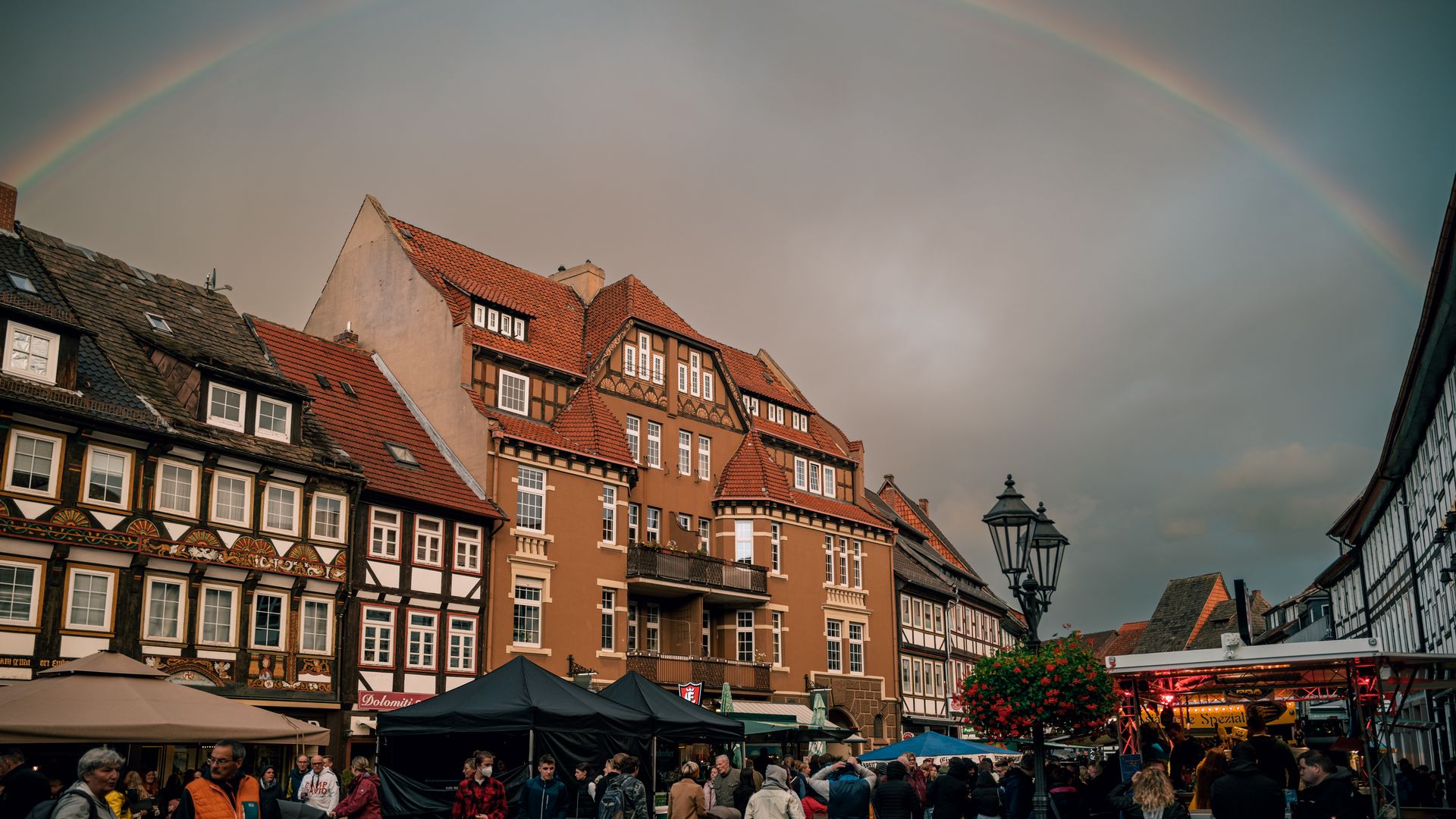 Der belebte Marktplatz beim Eulenfest mit vielen Menschen und einem Regenbogen.
