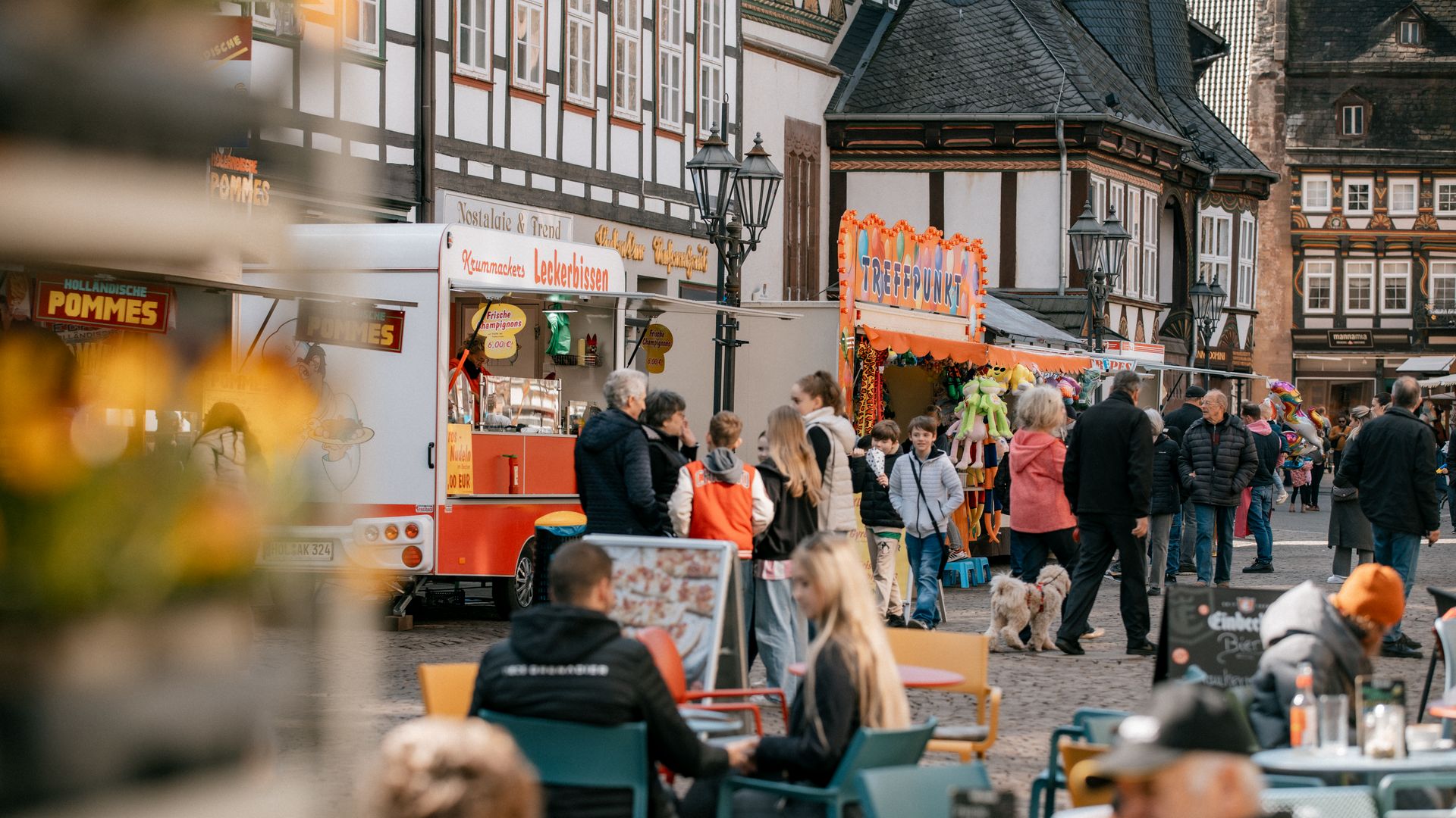 Frühjahrsmarkt in Einbeck mit Buden, Pommesstand und Besucher:innen in wundervoll detailreichen Fachwerkstraßen.
