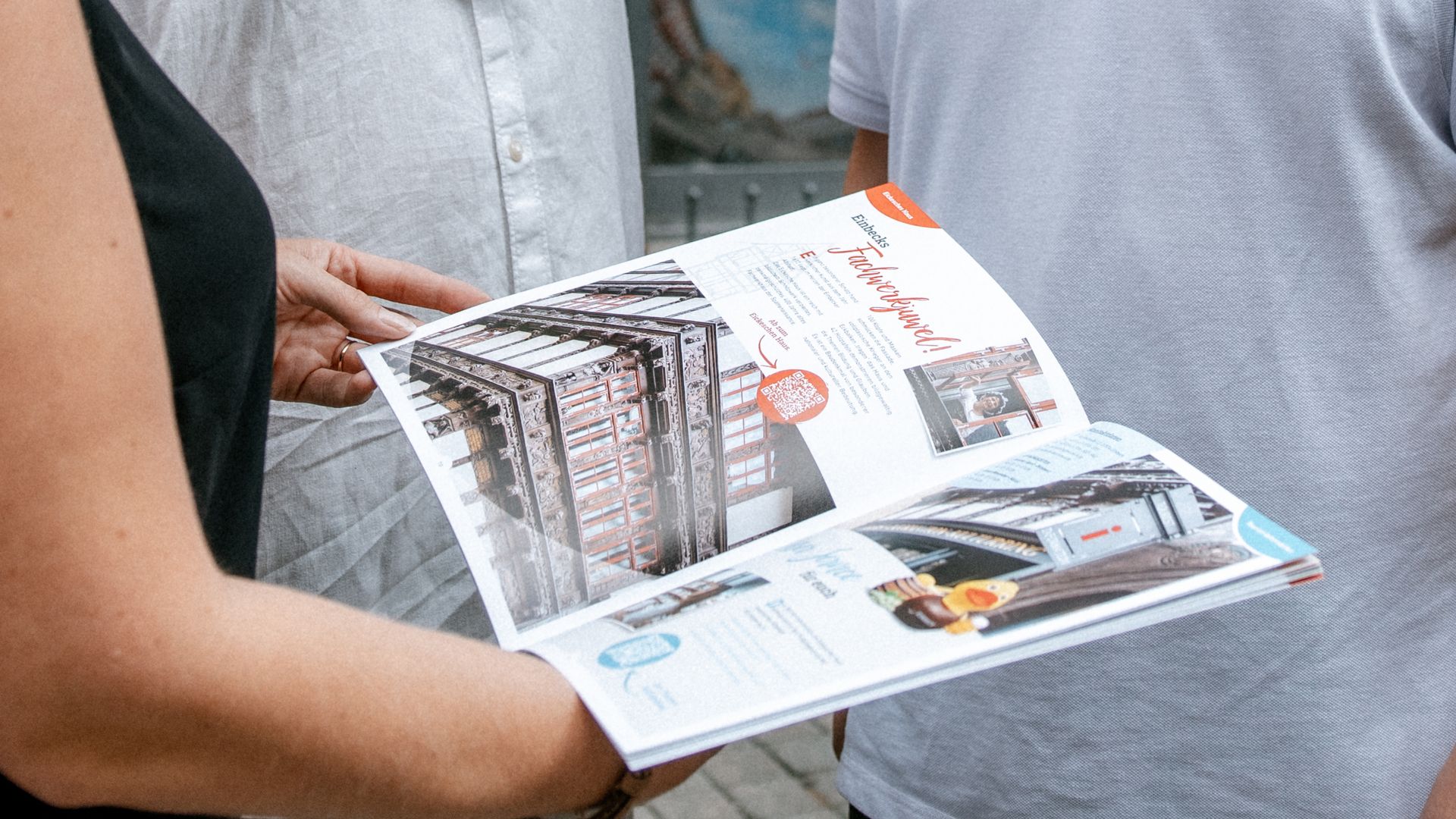 Eine Familie informiert sich vor der Tourist-Information Einbeck mit Stadtplan und lächelt einander zu.
