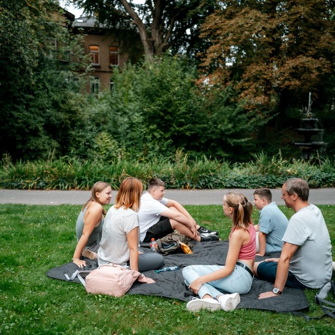 Familie sitzt auf Decke im Stiftsgarten Einbeck und genießt gemeinsam eine Pause im Grünen