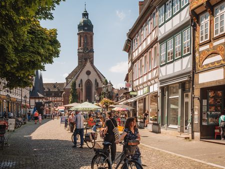 Sommerlicher Marktplatz in Einbeck mit Fachwerkhäusern und Kirche sowie vielen Menschen.